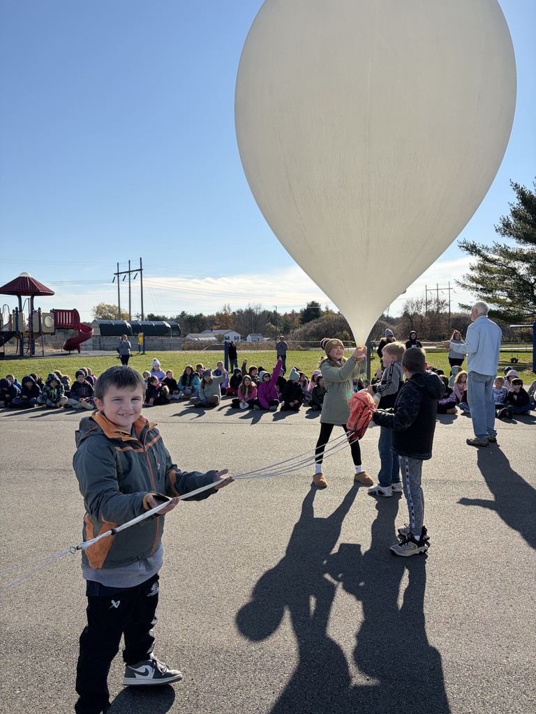 students watching as the balloon is getting prepared to take off.