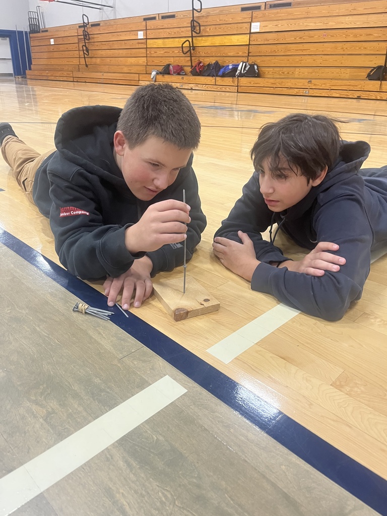 picture of two students trying to balance a nail on top of another nail. 