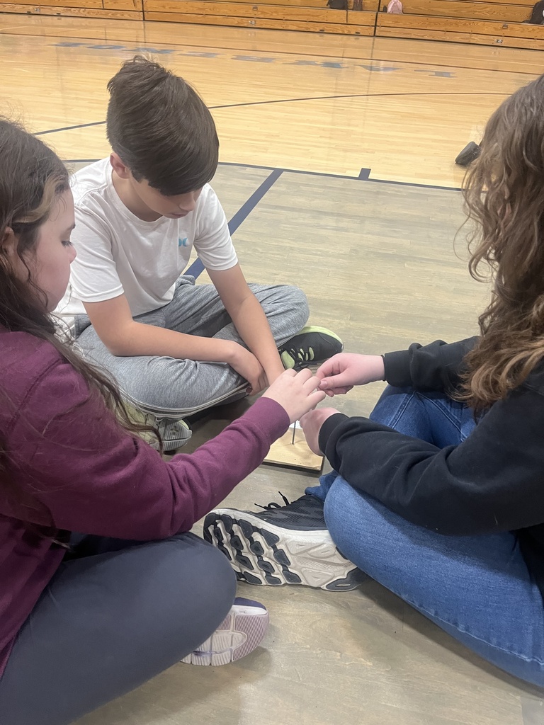 picture of two students trying to balance a nail on top of another nail. 