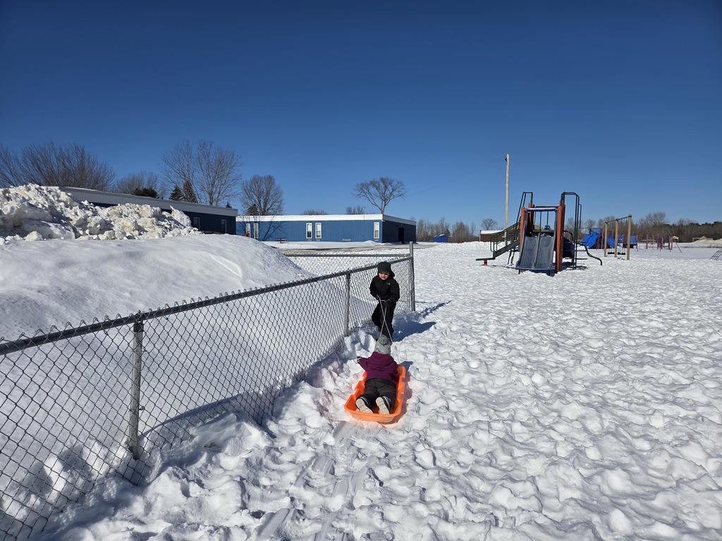 Picture shows a student pulling another student in a sled.