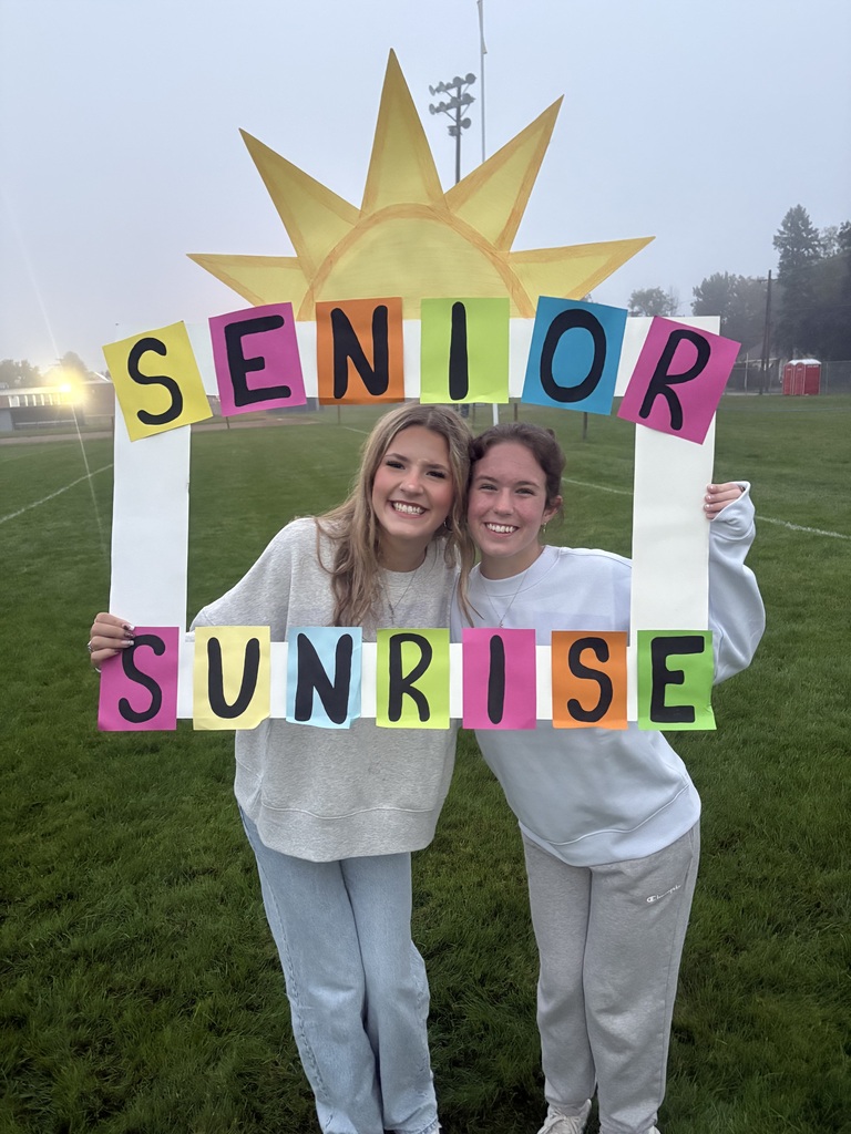 Two senior girls standing in front of the sunrise with a large picture frame around them that states, "Seniors".