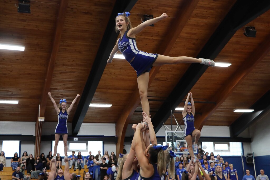 Cheerleader lifted in a pose, standing on one leg with the other extended backwards.