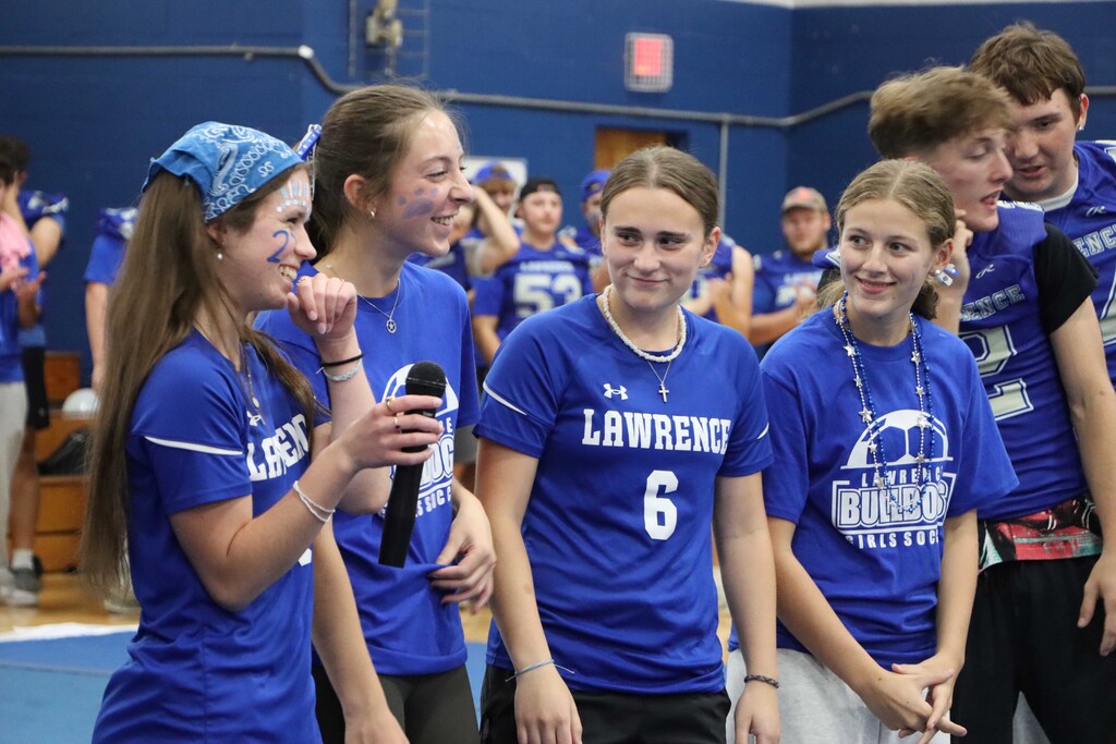 Five team captains with a microphone speaking with the student body