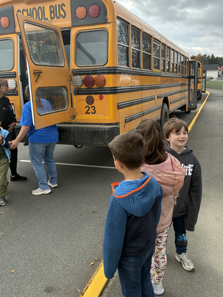 Students exit the emergency door at the back of a school bus with help from an adult