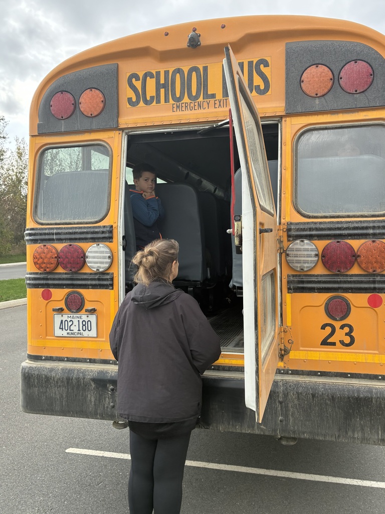 An adult waits to assist students practicing using the emergency door