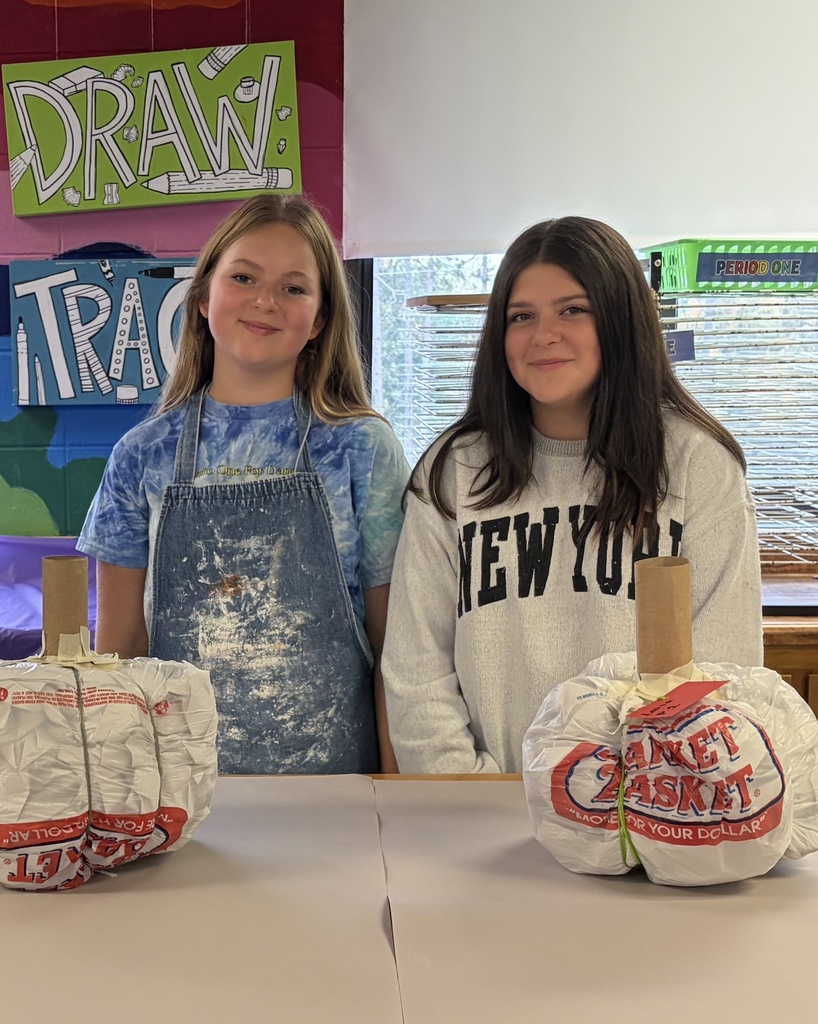 Two young ladies show their progress with their paper mache pumpkins, now in "the white"