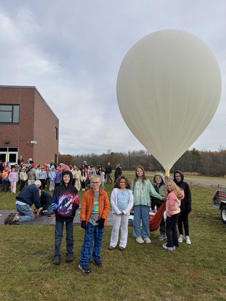 Students stand outside the school building preparing to lauch a weather ballon which will come down (by chance) in Bradlely, Maine.