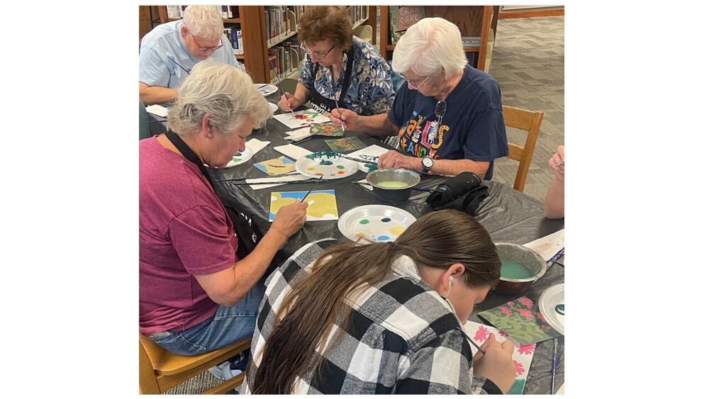 Several individuals are pictured here painting at a table