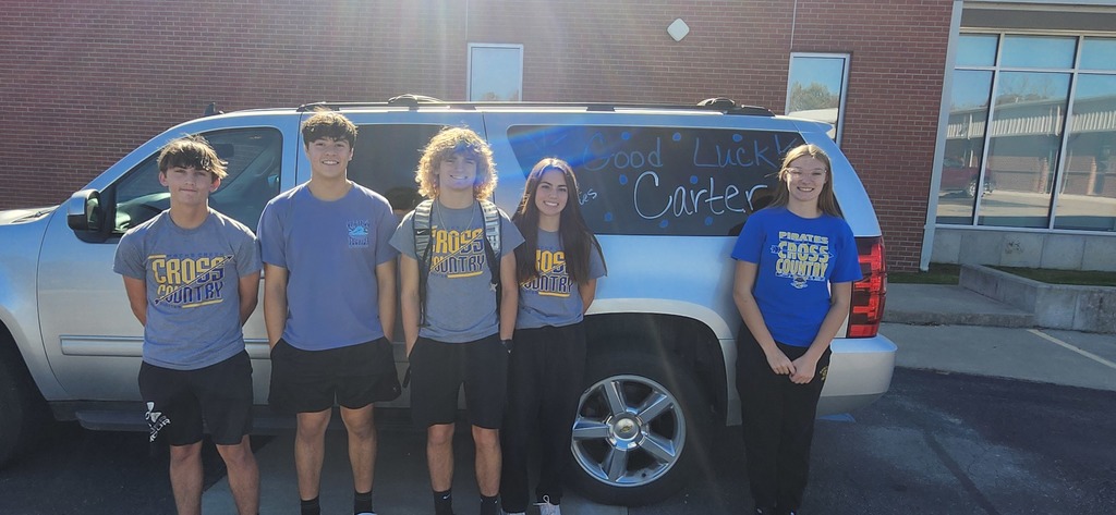 The XC team stands with Carter by the SUV before they head for State