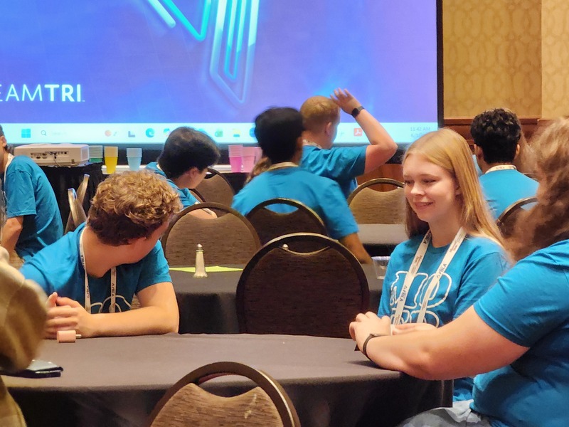 Maddie sits with other FBLA State officers at the training in Branson. She is pirctured at a table with several other students all around. 