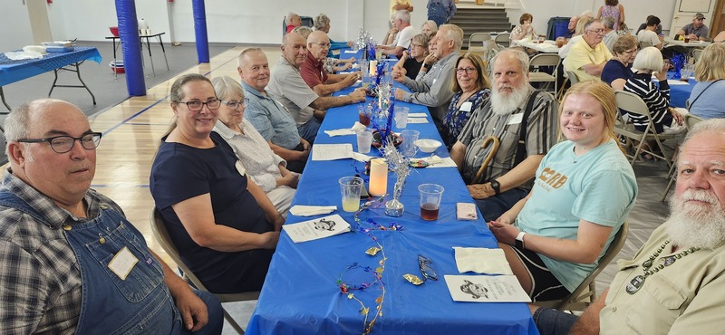 Another shot of length of tables with many alumni visiting