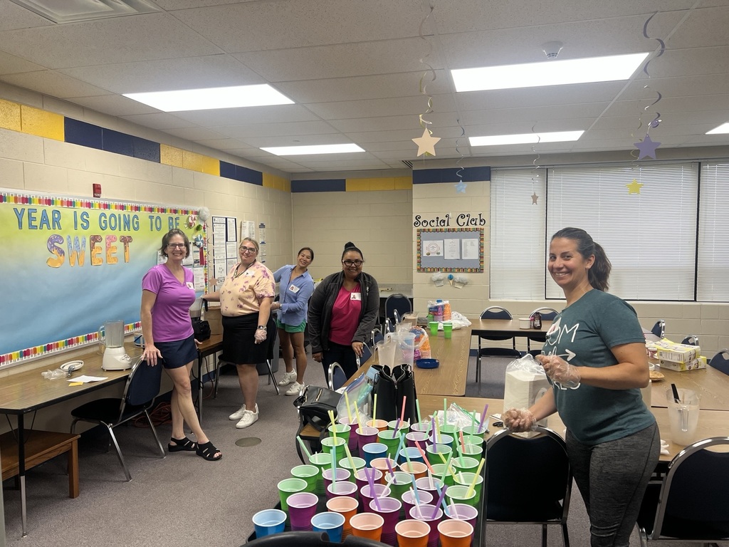 Teachers smile at the camera in a classroom while they make milkshakes
