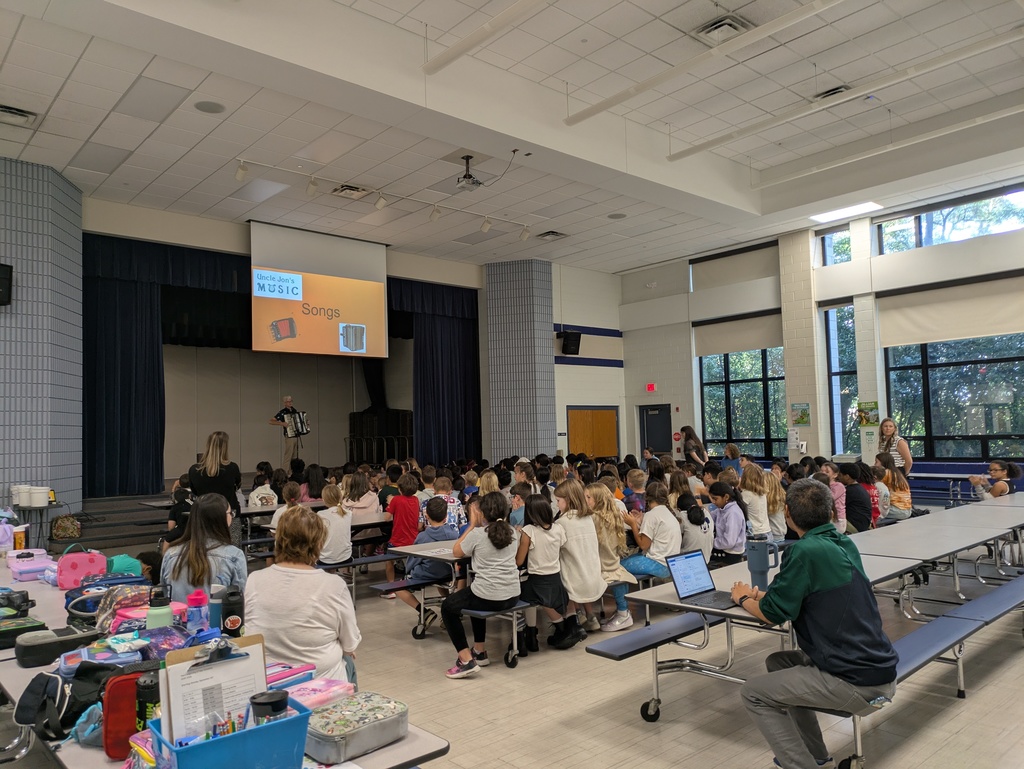Students sit in the cafeteria and watch the accordion performance