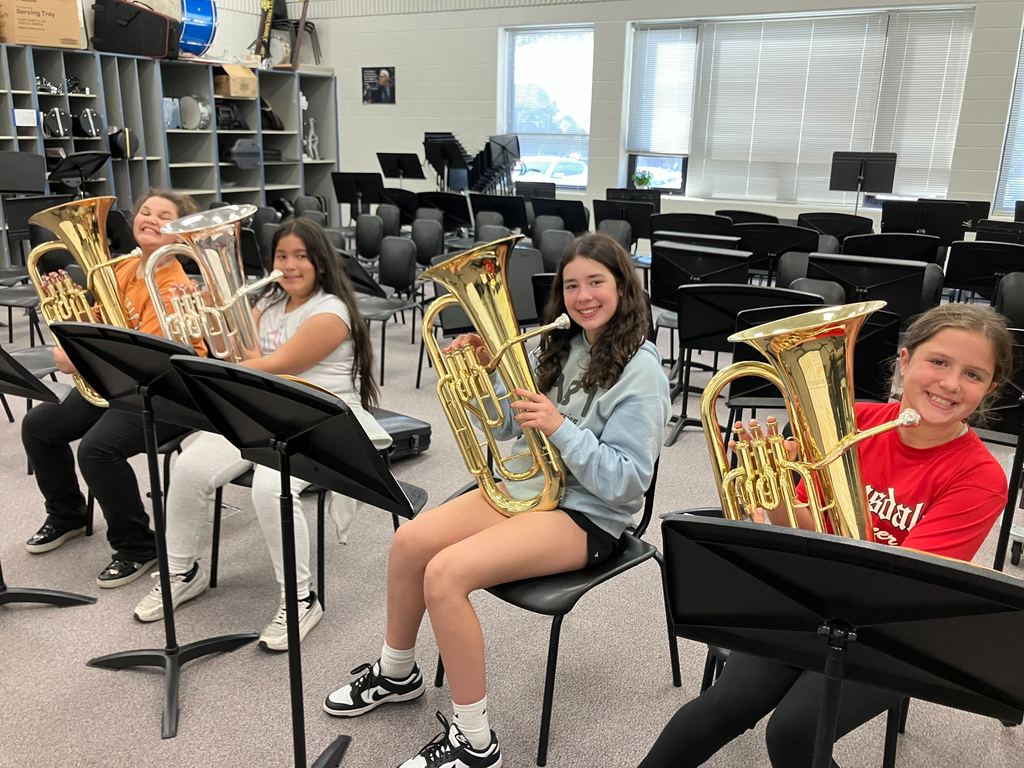 Students smile at the camera with wind instruments