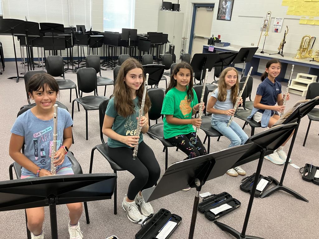 Students smile at the camera holding their wind instruments