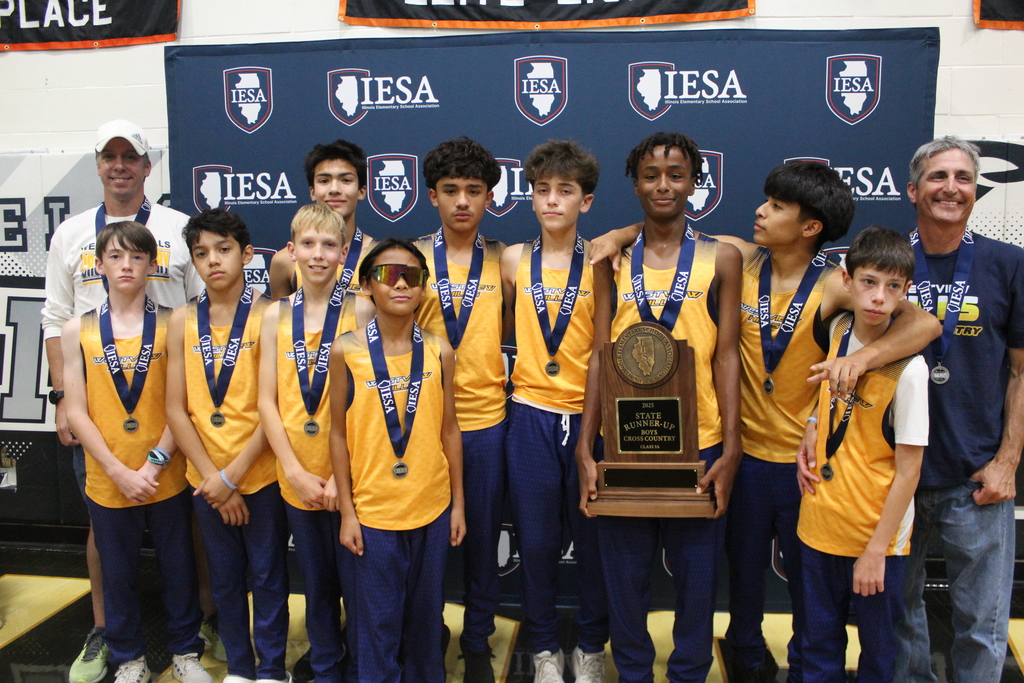 The boys cross country team poses with their medals and trophy