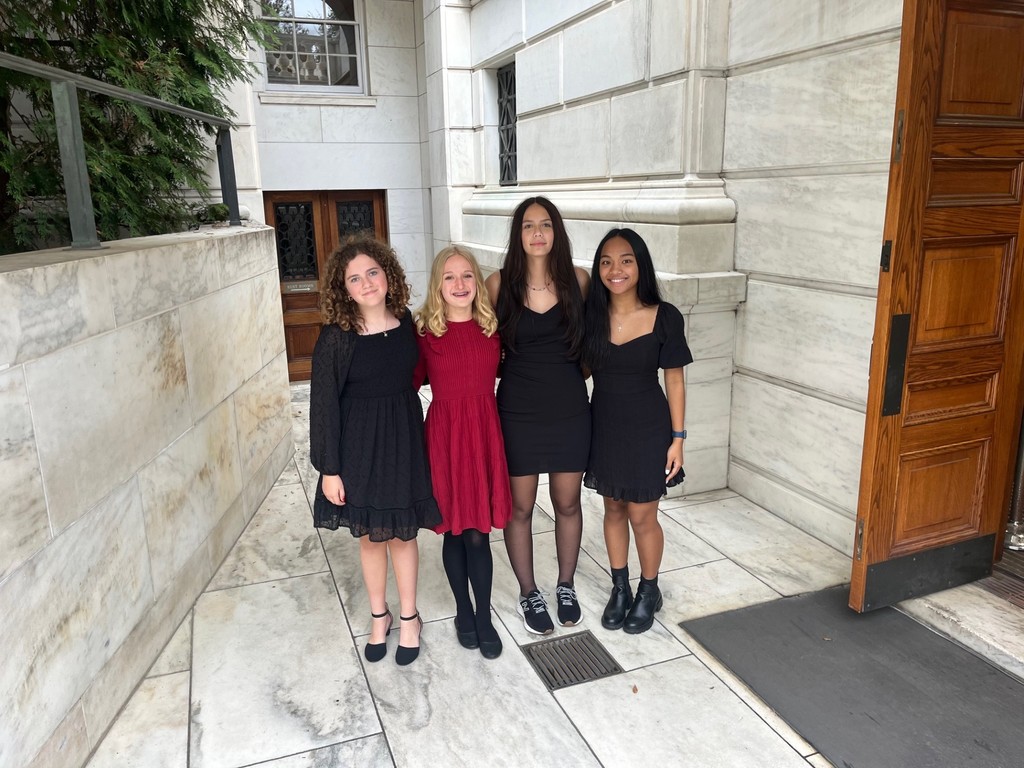 Four students in dresses pose in a building