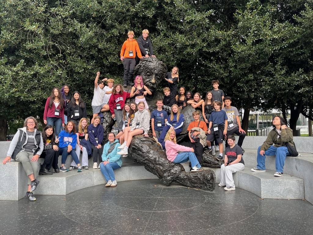 Students and staff pose at a sculpture