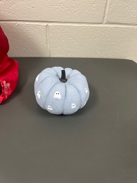 A small pumpkin painted blue with little painted ghosts on it