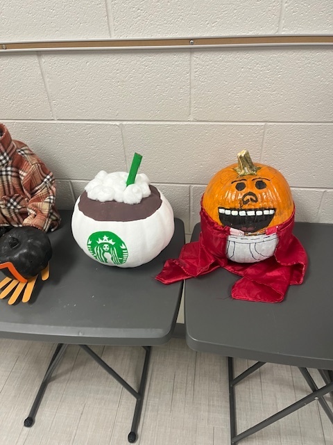 A pumpkin on the left decorated to look like a latte, and a pumpkin on the right decorated like Captain Underpants