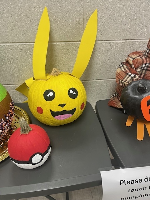A pumpkin decorated to look like Pikachu with a smaller pumpkin next to it painted like a poke ball