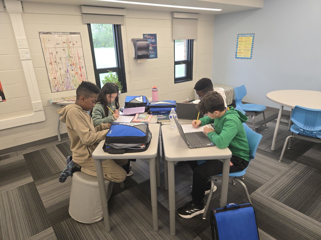Four students sitting at desks and writing
