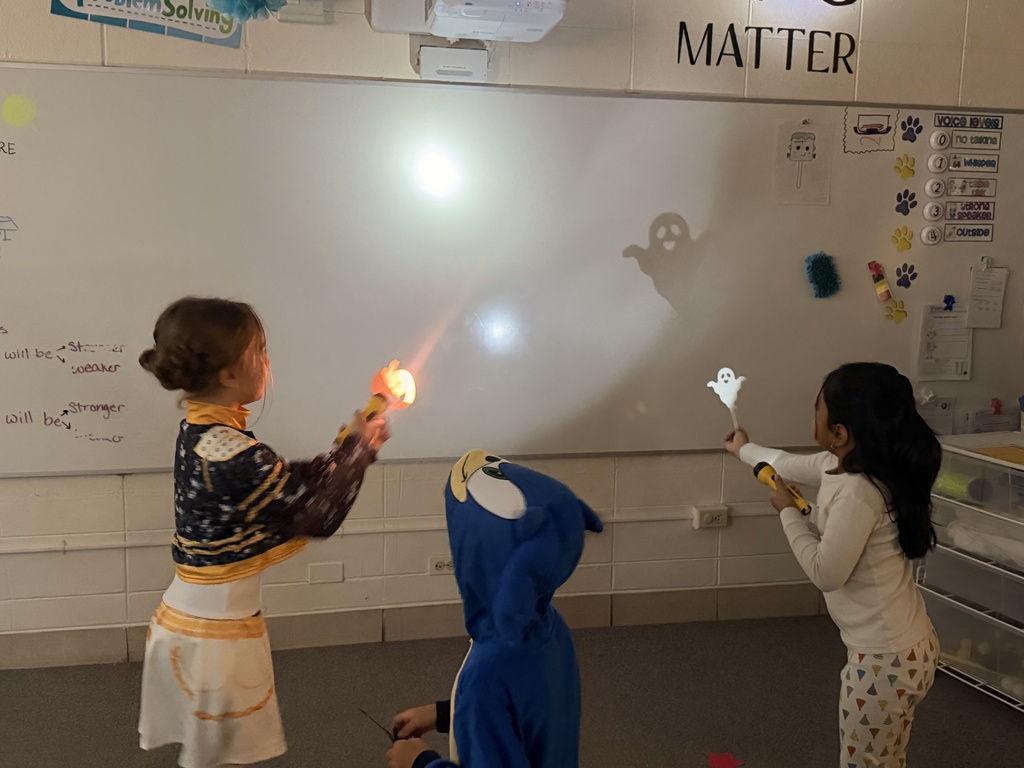 Students make shadows around the room using paper and flashlights