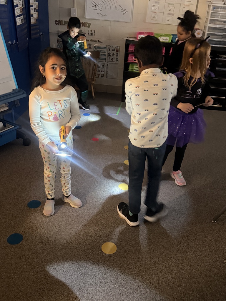 Students make shadows around the room using paper and flashlights
