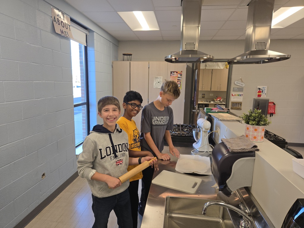 Three students work on making pizza in class