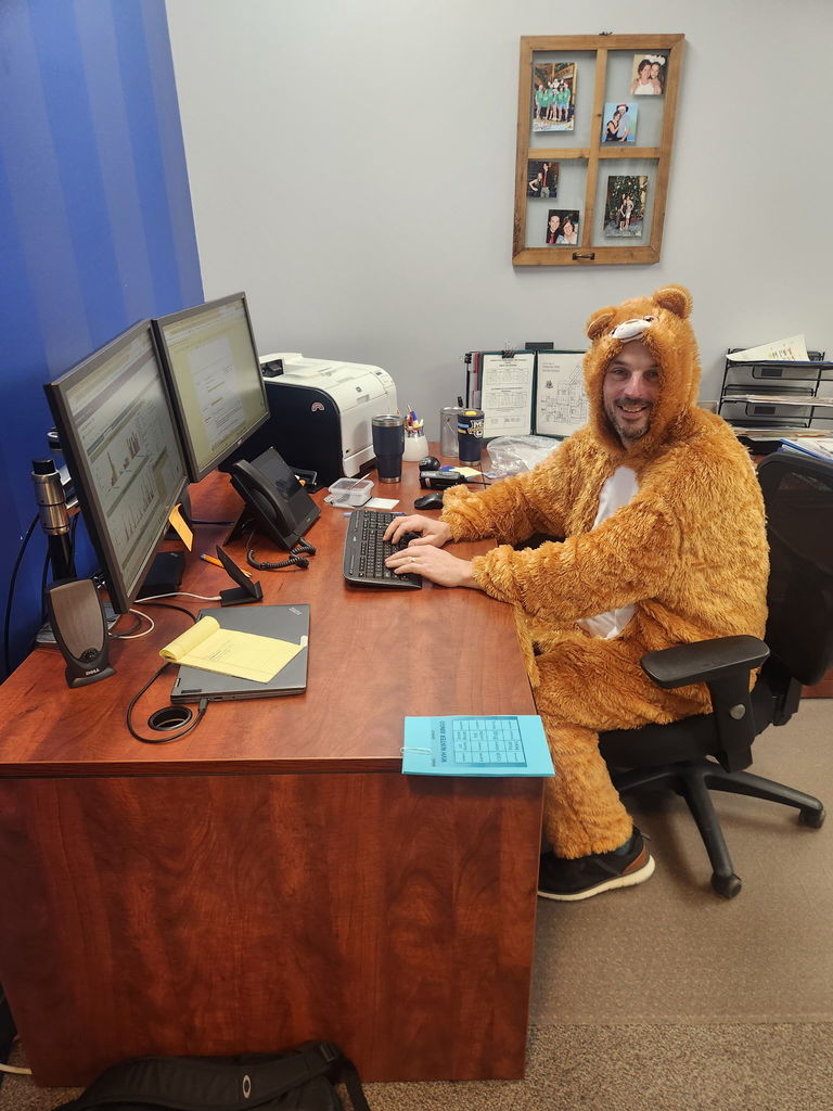 A staff member rocks a onesie while sitting at a desk