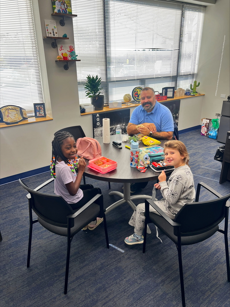 Students smile at a table with the principal