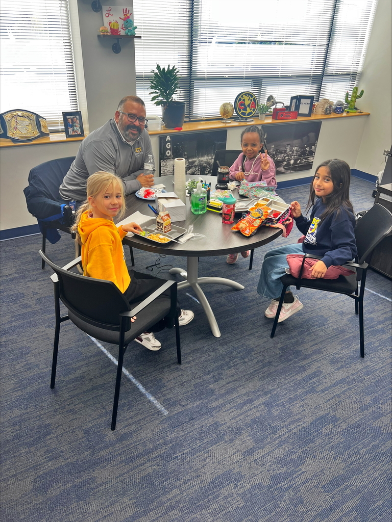 Students smile at a table with the principal