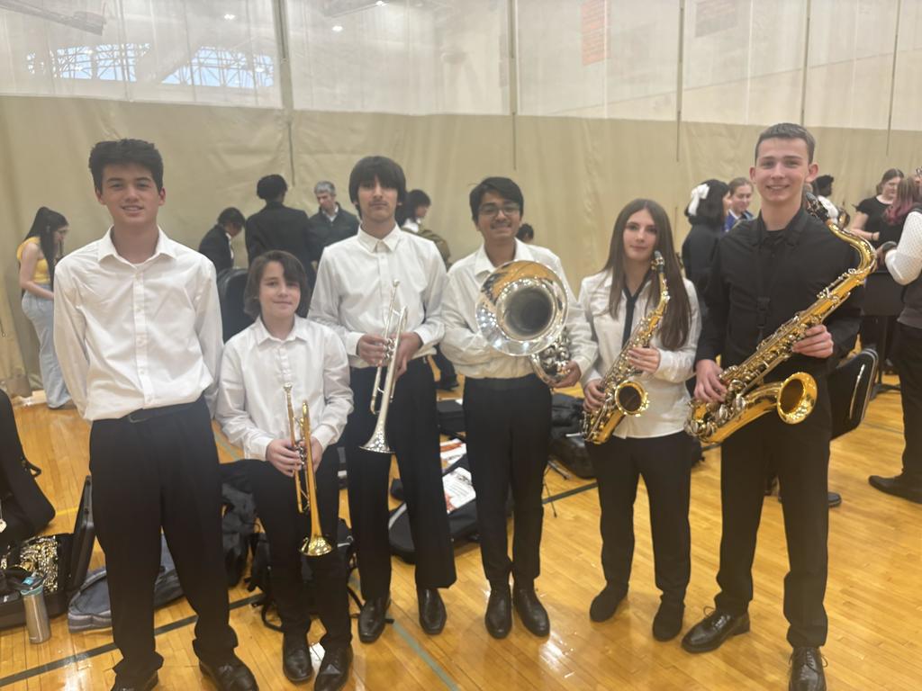Students pose for the camera holding instruments. They are dressed up and ready to perform.