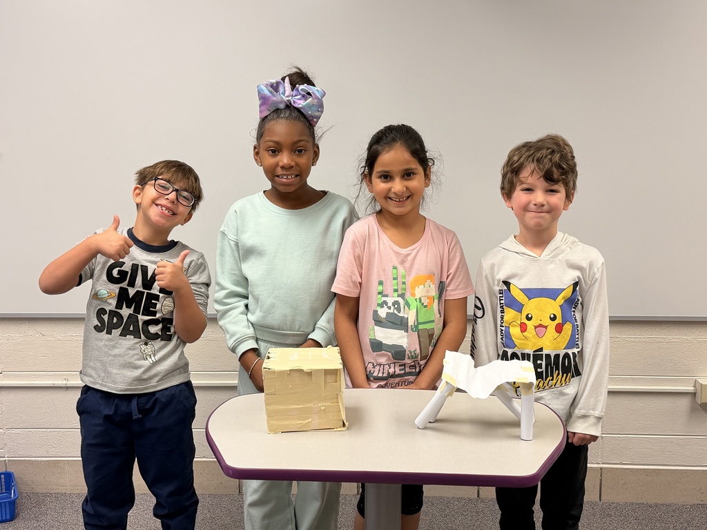 Four students pose together and smile with their project