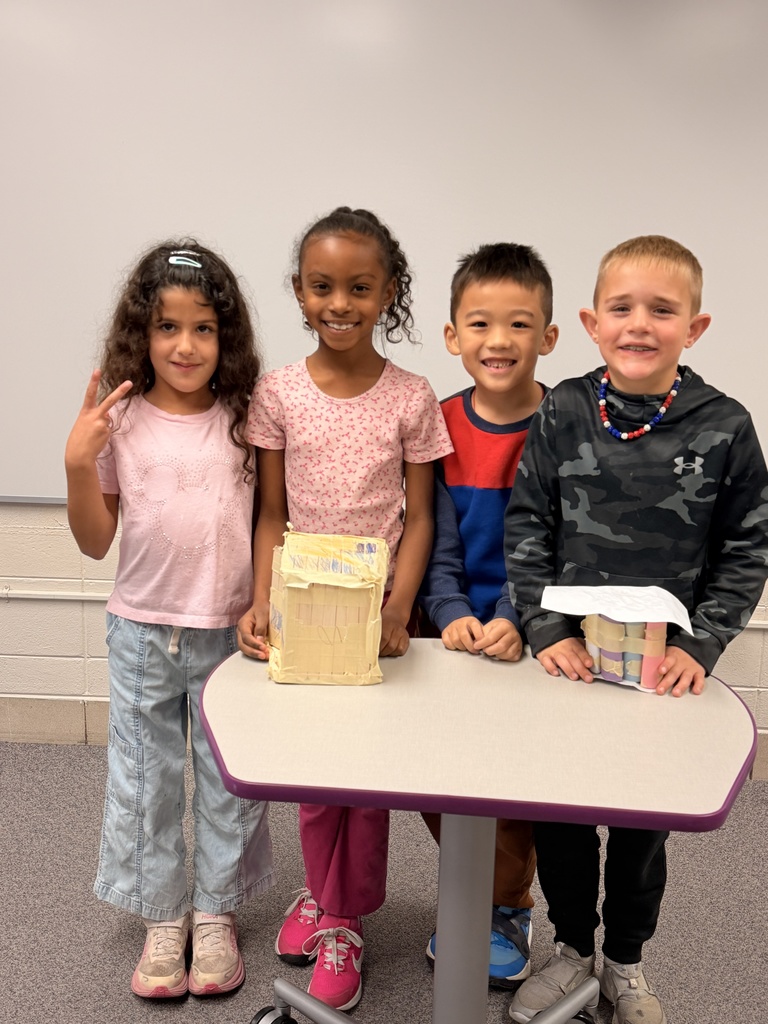 Four students pose together and smile with their project