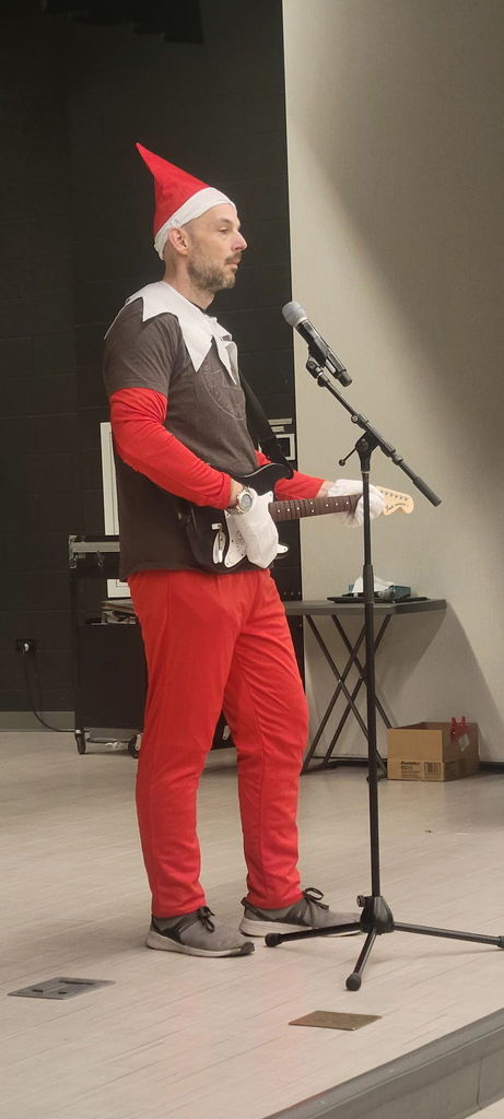Principal dressed as an elf holding a guitar