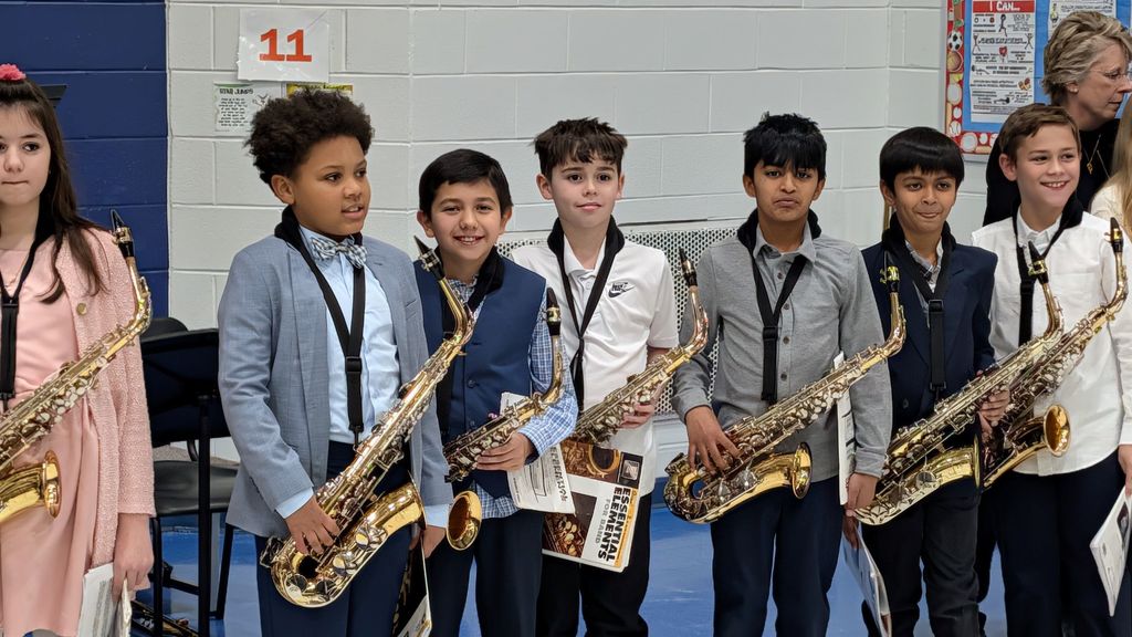 Students hold their instruments and stand in a line during the concert