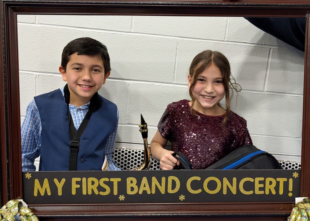 Students smile behind a picture frame with the words, "My first band concert"