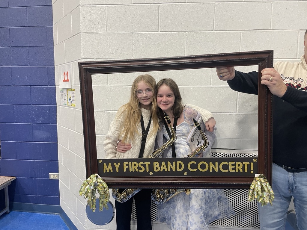 Students smile behind a picture frame with the words, "My first band concert"