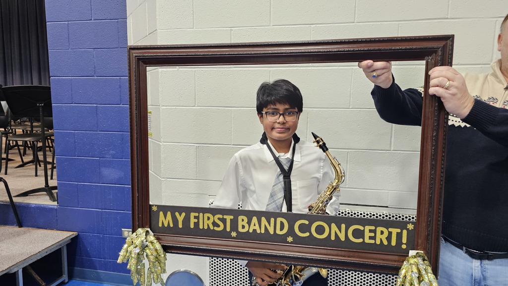 Students smile behind a picture frame with the words, "My first band concert"