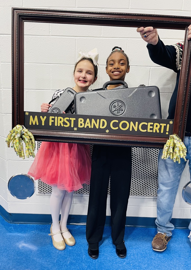Students smile behind a picture frame with the words, "My first band concert"