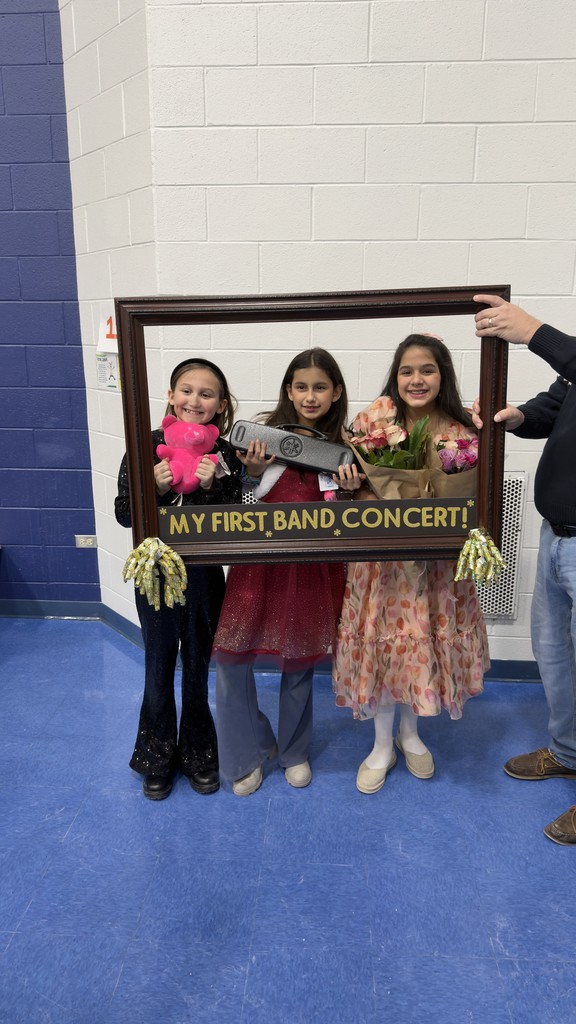 Students smile behind a picture frame with the words, "My first band concert"