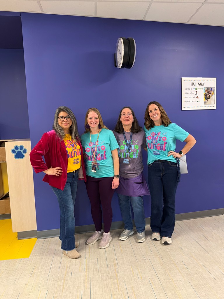 Teachers pose with matching t-shirts that read, "Que bonito ser bilingue"