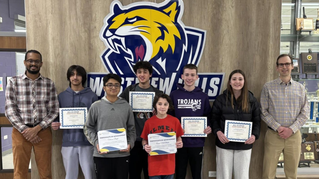 Students in a group smile at the camera holding up their recognition papers
