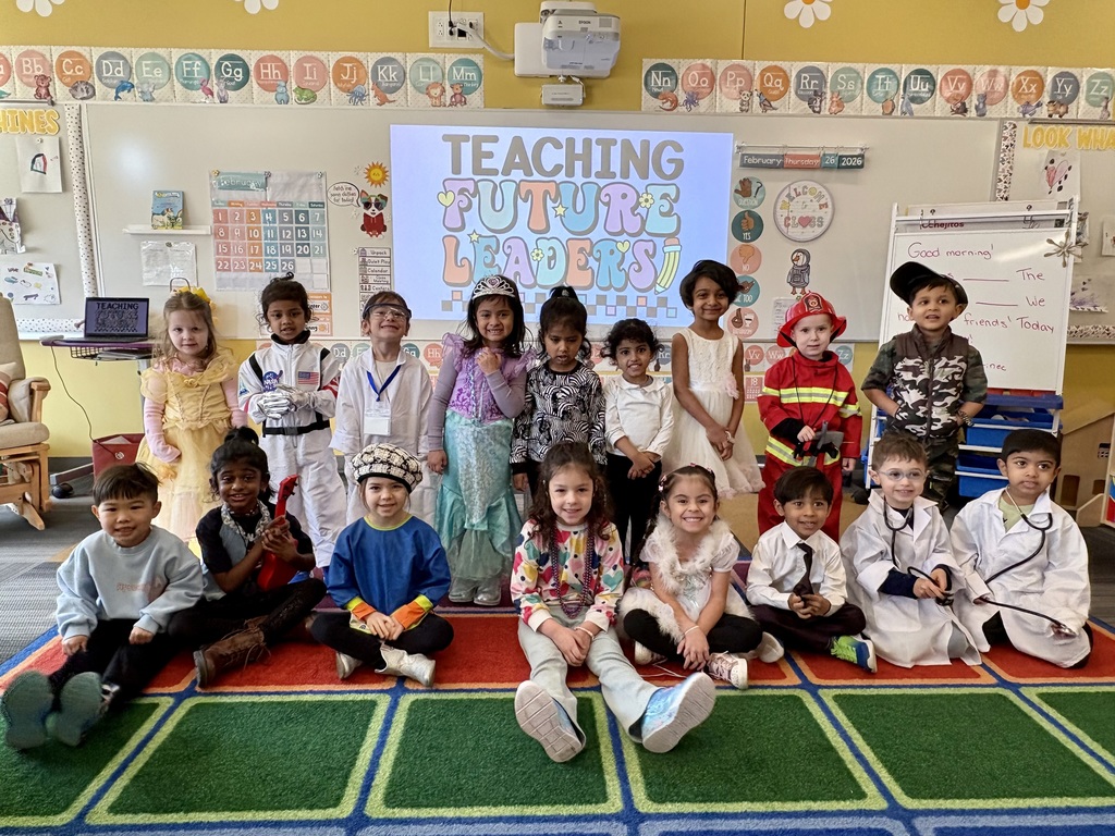 The classroom full of preschoolers dressed in uniforms poses for a photo.