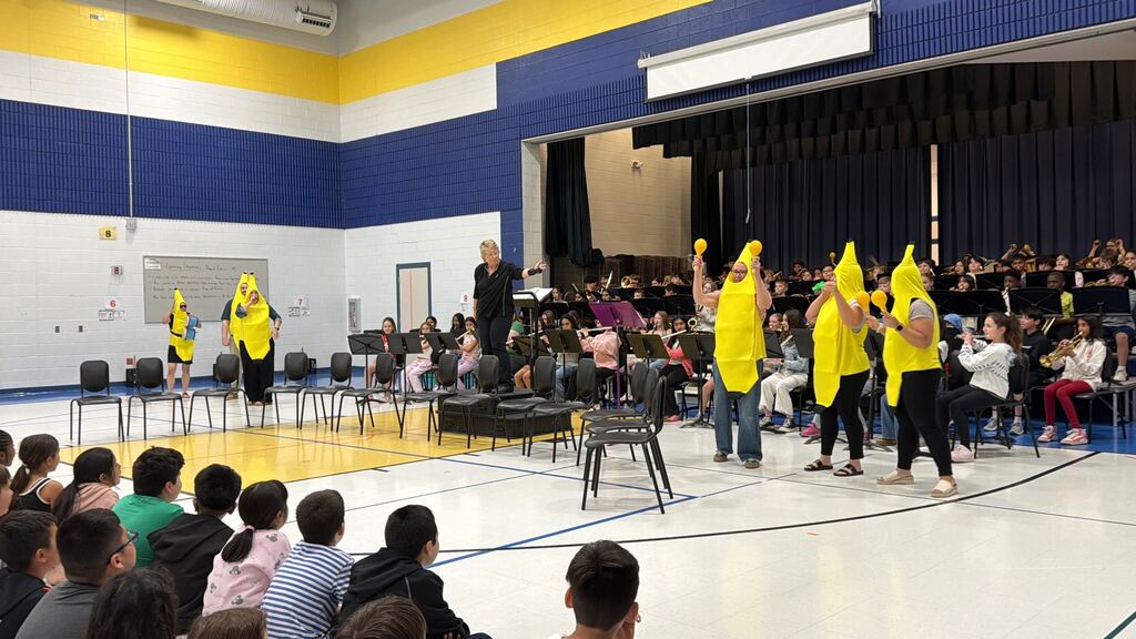 The band performs while teachers dressed in banana costumes shake maracas