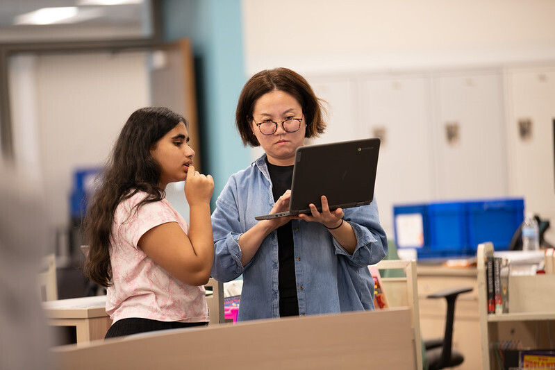 A teacher works with a student on a computer