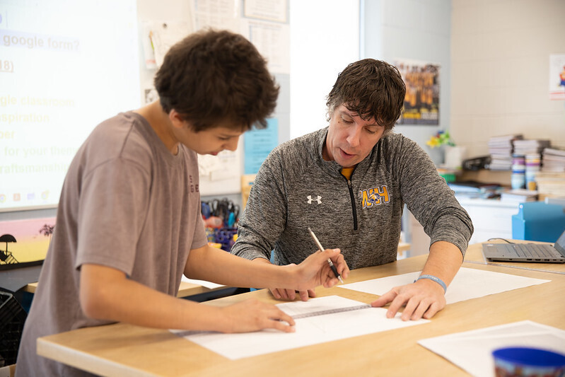 A teacher and student work together at a table