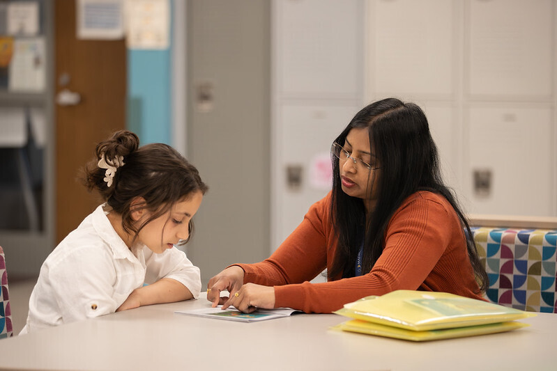 A teacher and student work together at a table
