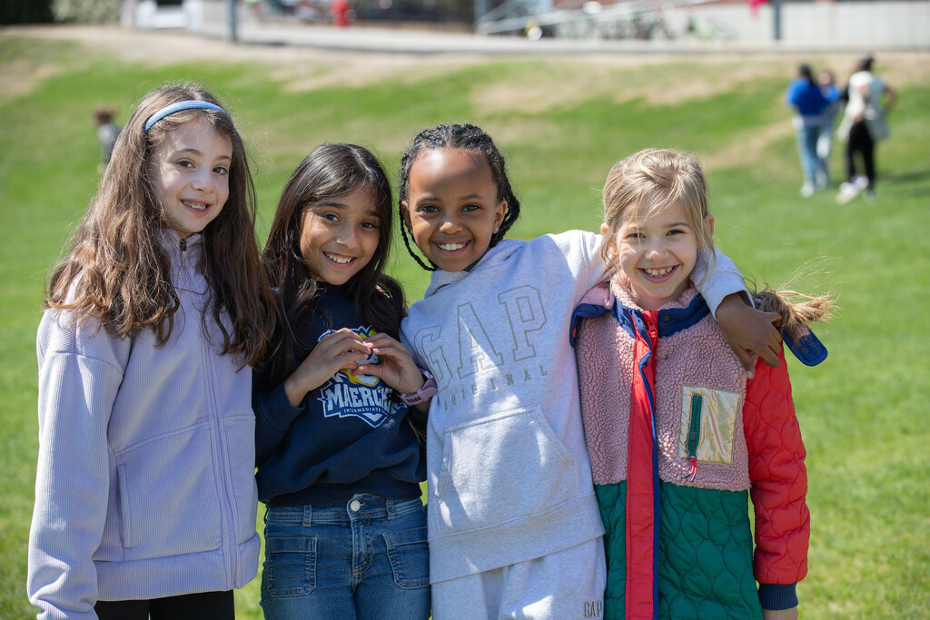 Four students smile at the camera outside